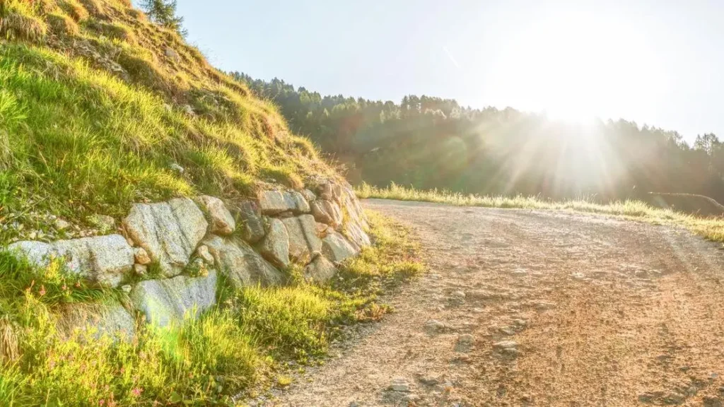 Sunlit road through green hills at sunrise illustrating what is the kingdom of God
