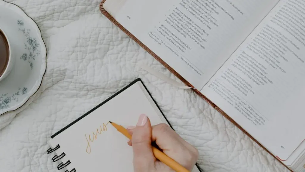 Hand writing self forgiveness Bible study notes beside an open Bible and coffee